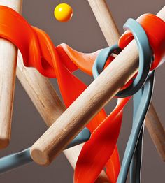 an orange and blue ball is in between two wooden sticks that are connected to each other