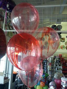 some balloons that have been dyed red and are hanging from the ceiling in a store