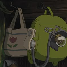 a green backpack hanging from the side of a wall next to a bag with a camera on it