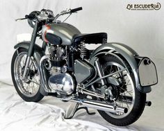 a silver motorcycle is parked on a white sheeted surface with the words escudera above it