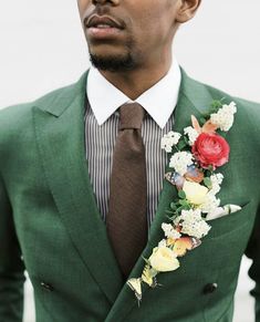 a man wearing a green suit with flowers in his lapel