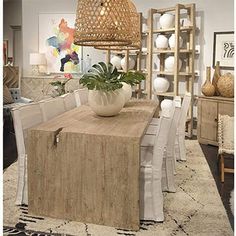 a wooden table topped with a white vase filled with green plant sitting on top of it