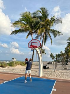 two men playing basketball on an outdoor court with palm trees in the backgroud