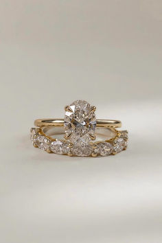 two gold wedding rings with diamonds on each one and an oval shaped diamond in the middle