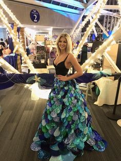 a woman in a dress made out of sea shells standing on the floor at a convention