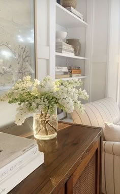 a vase with white flowers sitting on top of a wooden table next to a couch