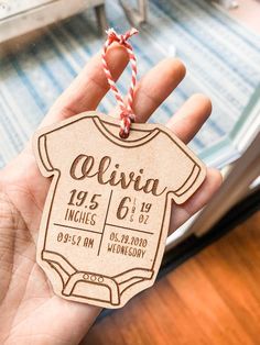 a person holding up a wooden baby announcement ornament with twine on it