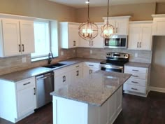 an empty kitchen with white cabinets and granite counter tops, stainless steel appliances and wood floors