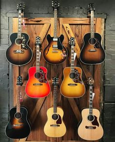 an assortment of guitars hanging on a wall