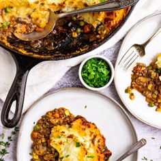 two white plates topped with food next to a skillet filled with shepherd's pie