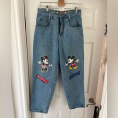 a pair of jeans with mickey and minnie mouse patches on them hanging from a door