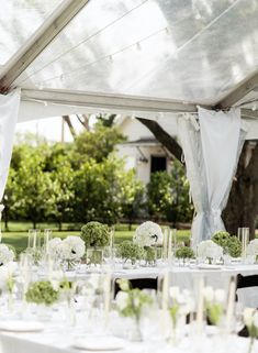 the tables are set up with white flowers and greenery for an outdoor wedding reception