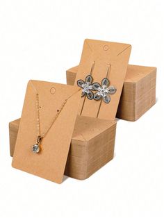 two boxes with necklaces in them and one has a flower on the front, while the other has a chain attached to it