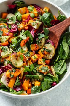 a salad with carrots, radishes and spinach in a white bowl