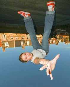 a man is upside down on the ground with his feet in the air and buildings reflected in the water