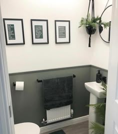 a white toilet sitting in a bathroom next to a wall with pictures on the walls