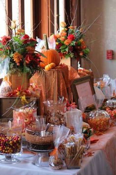 a table covered in candy and candies with pumpkins on top, flowers behind it