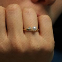 a woman's hand holding a pearl and diamond ring