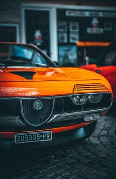 an orange car parked in front of a gas station with two other cars behind it