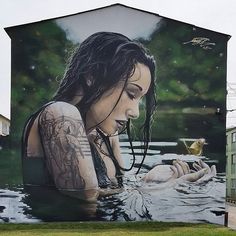 a man standing in front of a large painting on the side of a building with a woman swimming