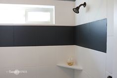 a bathroom with black and white stripes on the walls, shower head, and shelf