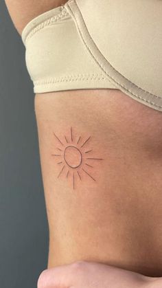 a woman's stomach with a small sun tattoo on it