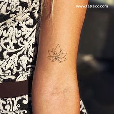 a woman's arm with a small flower tattoo on the left side of her arm