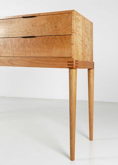 a wooden table with two drawers on one side and an angled leg on the other