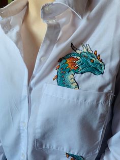 a person wearing a white shirt with a blue dragon embroidered on the chest and sleeves