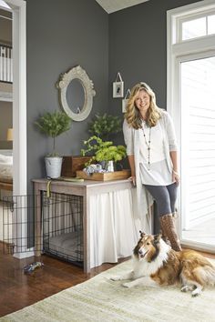 a woman standing next to a dog in front of a table with plants on it