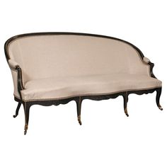 an antique style couch with black trim and white upholstered fabric on the back