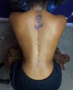 the back of a woman's neck with a rose tattoo on her lower back