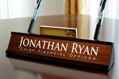 a wooden sign with two pens on it that says jonathan ryan chief financial official officer