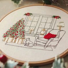 a cross stitch christmas scene with a couch, tree and dog in the living room