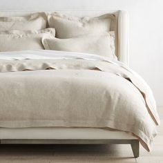 a bed with white linens and pillows in a minimalistic bedroom setting on a hard wood floor