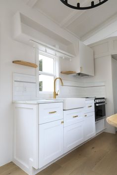 a kitchen with white cabinets and gold handles on the faucet above the sink