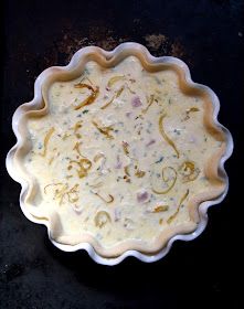 an uncooked pie crust sitting on top of a black table with white icing