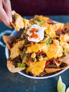 a bowl filled with nachos and cheese on top of tortilla chips