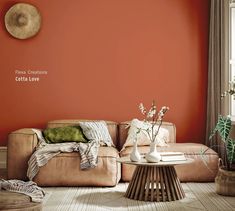 a living room with an orange wall and white vases on the coffee table in front of it