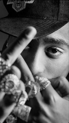 a black and white photo of a young man wearing a hat with his fingers in the air