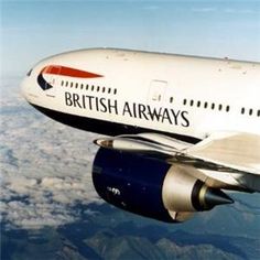 an airplane flying in the sky above some clouds and land below it is blue, white, and red