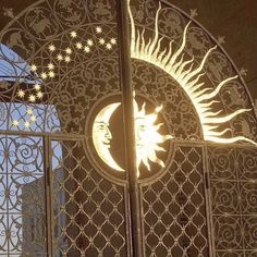 the sun and moon are lit up in front of an iron gate with intricate designs