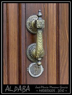 an ornate door handle on a wooden door with the word al daba written below it