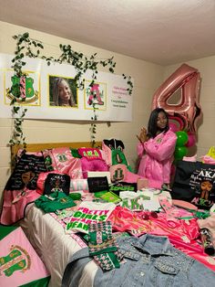 a woman standing in front of a bed covered in pink and green items with balloons