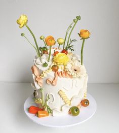 a white cake decorated with flowers and vegetables