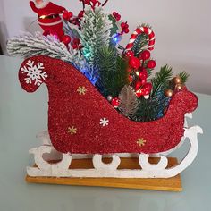 a red sleigh with christmas decorations and lights on the top is sitting on a table