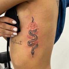 a woman's stomach with a snake and rose tattoo on her side ribcage