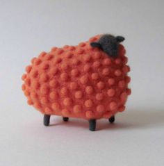 an orange toy sheep with black feet on a white surface