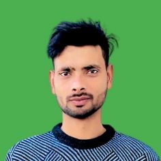 a man with black hair wearing a blue and white sweater looking at the camera while standing in front of a green background