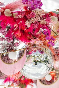 some disco balls and flowers hanging from the ceiling